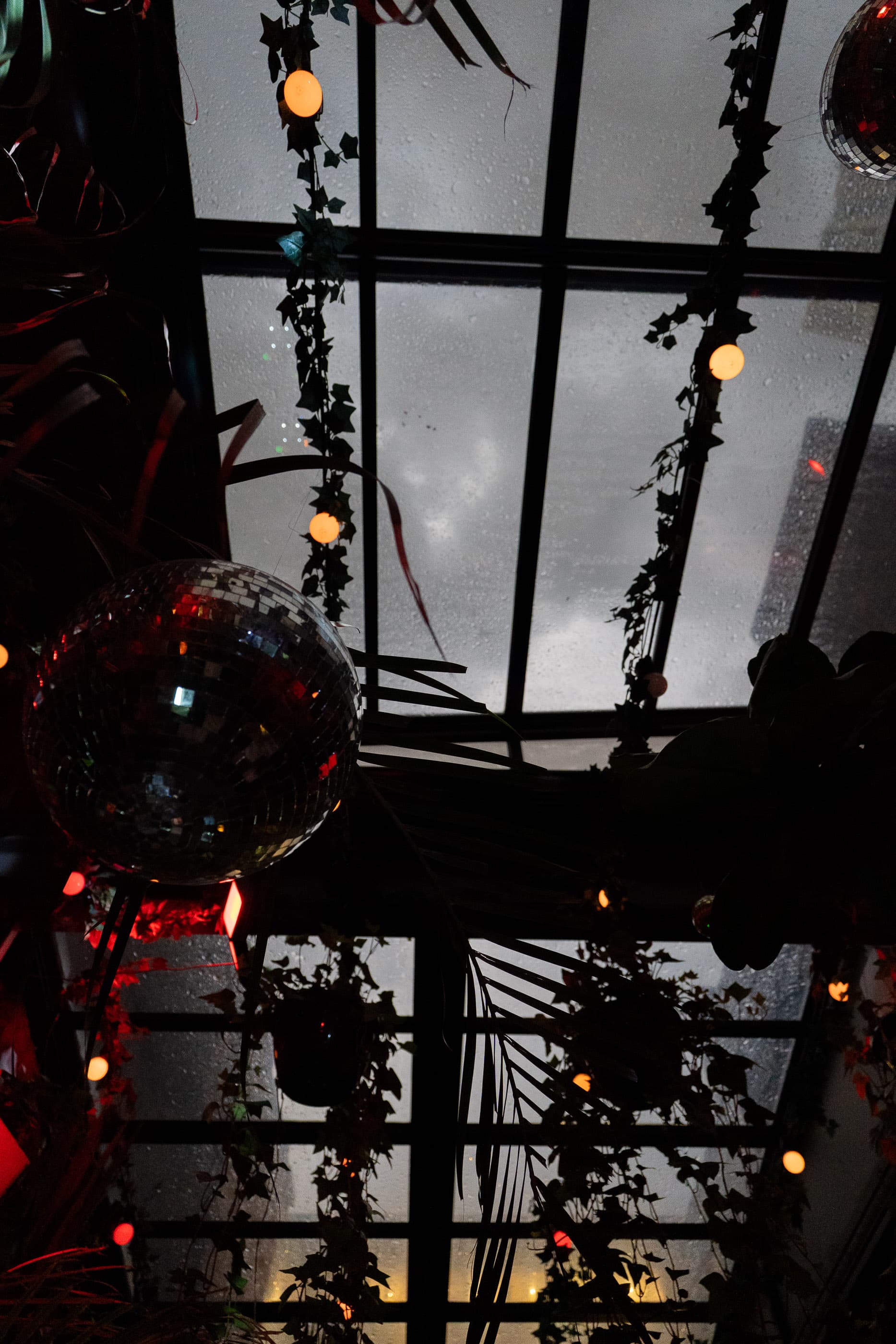 Disco ball and string lights under a glass-roofed venue