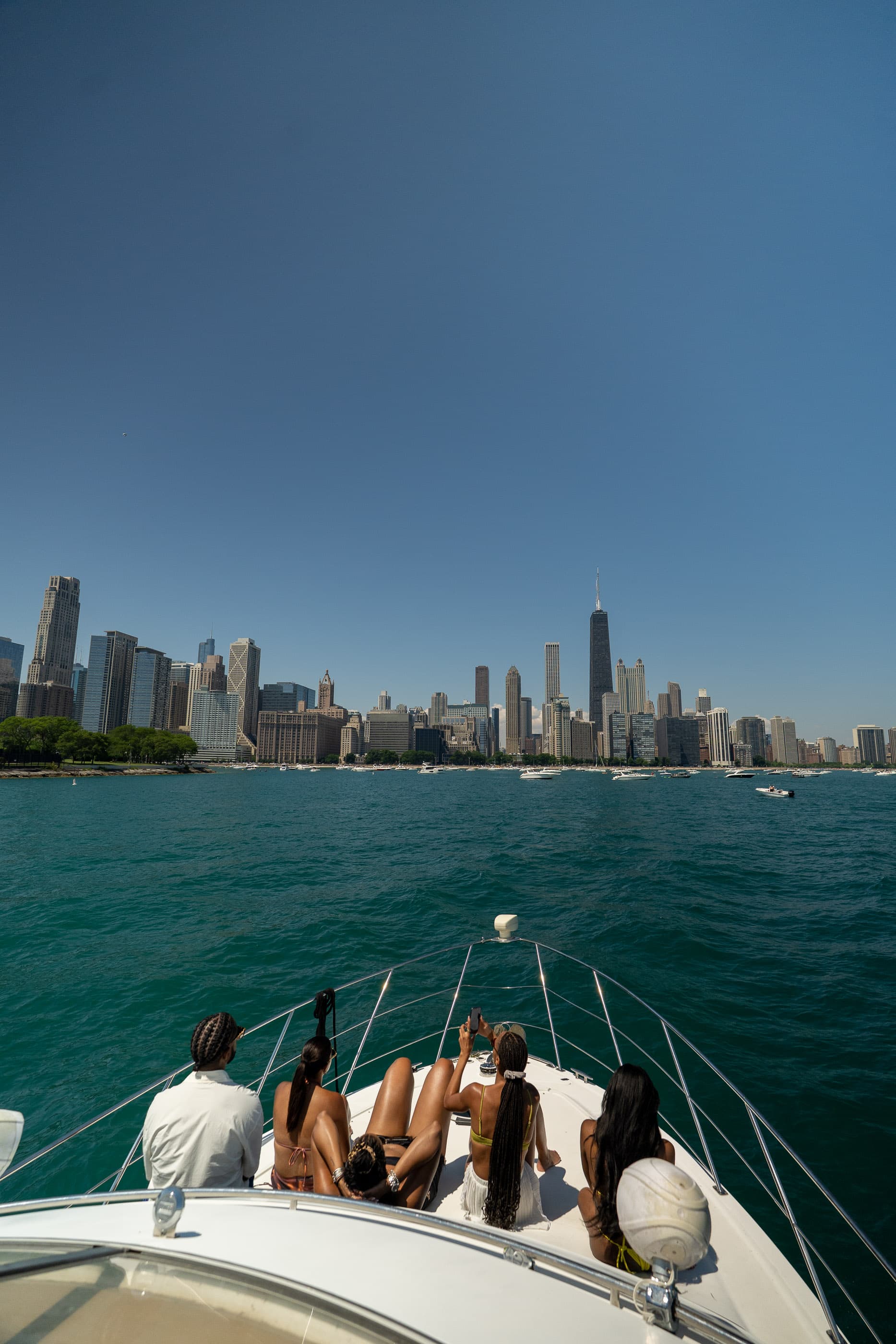 Friends on the bow of a boat heading toward the Chicago skyline