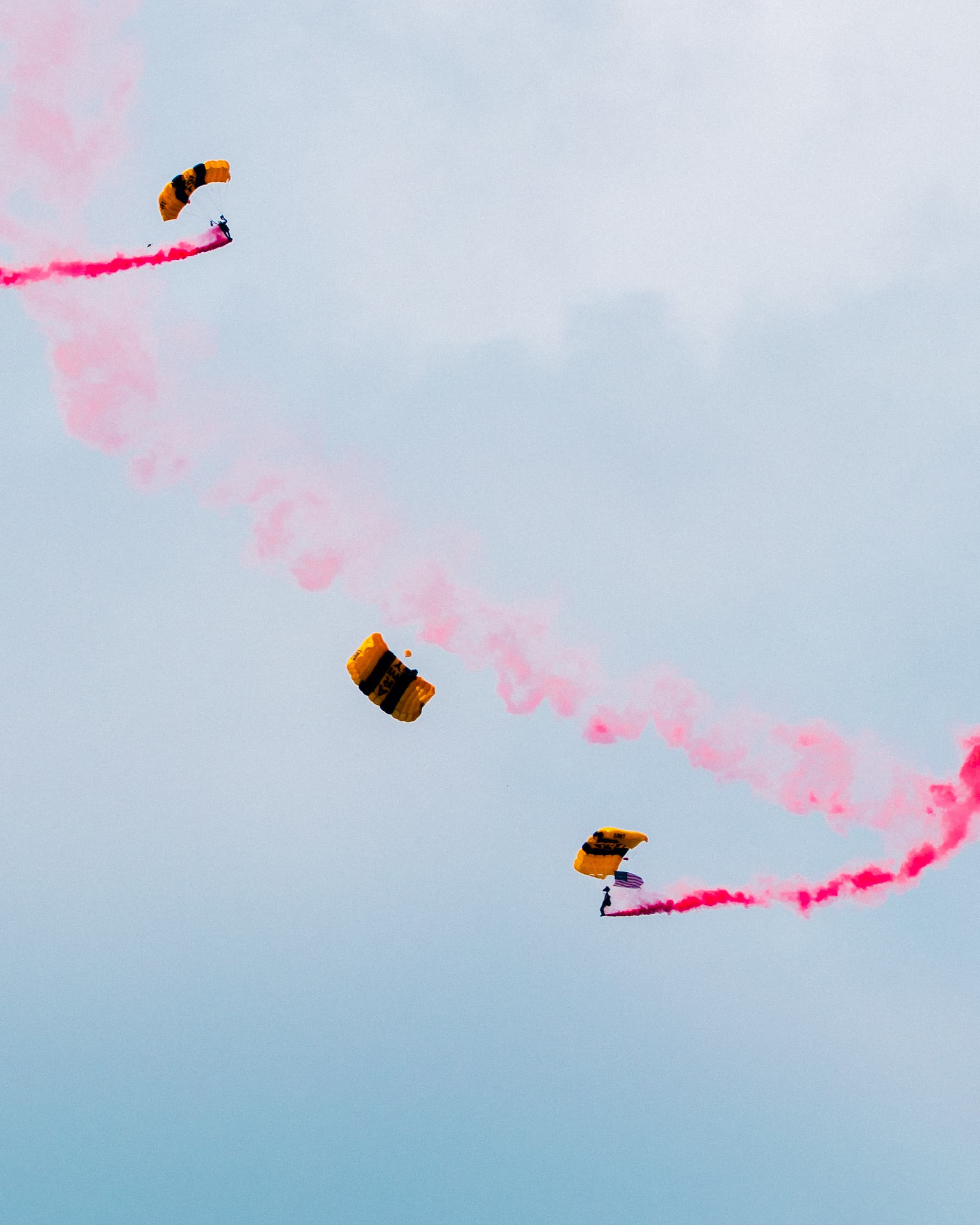 Parachutists trailing pink smoke across the sky