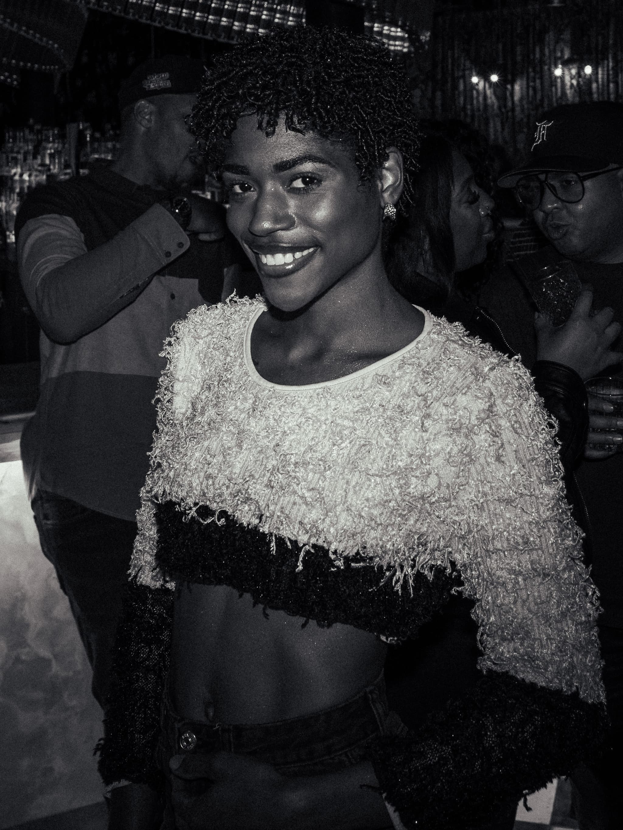 Black and white portrait of a smiling woman in a fuzzy cropped top at a night event