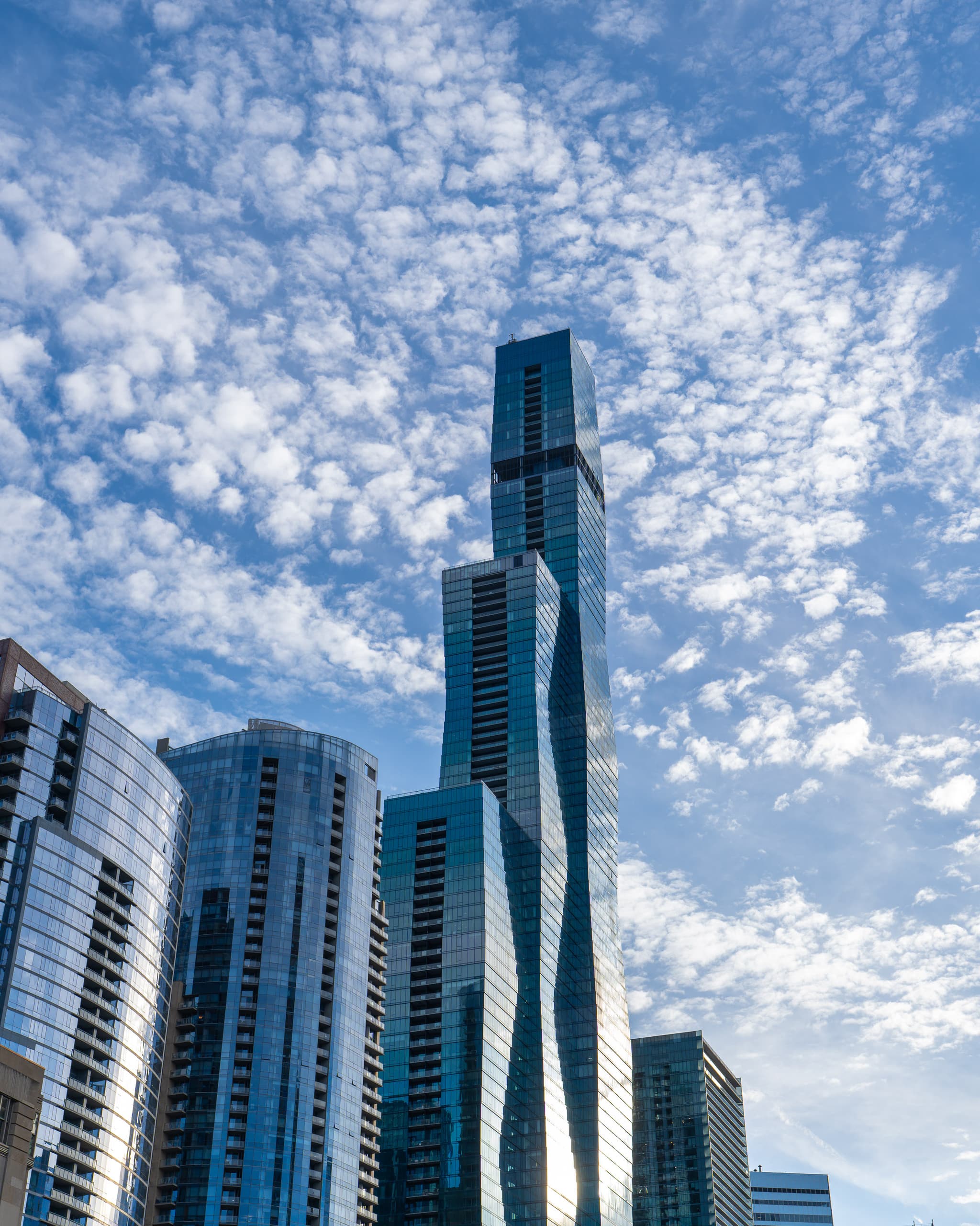 Glass skyscraper rising into a sky full of scattered clouds