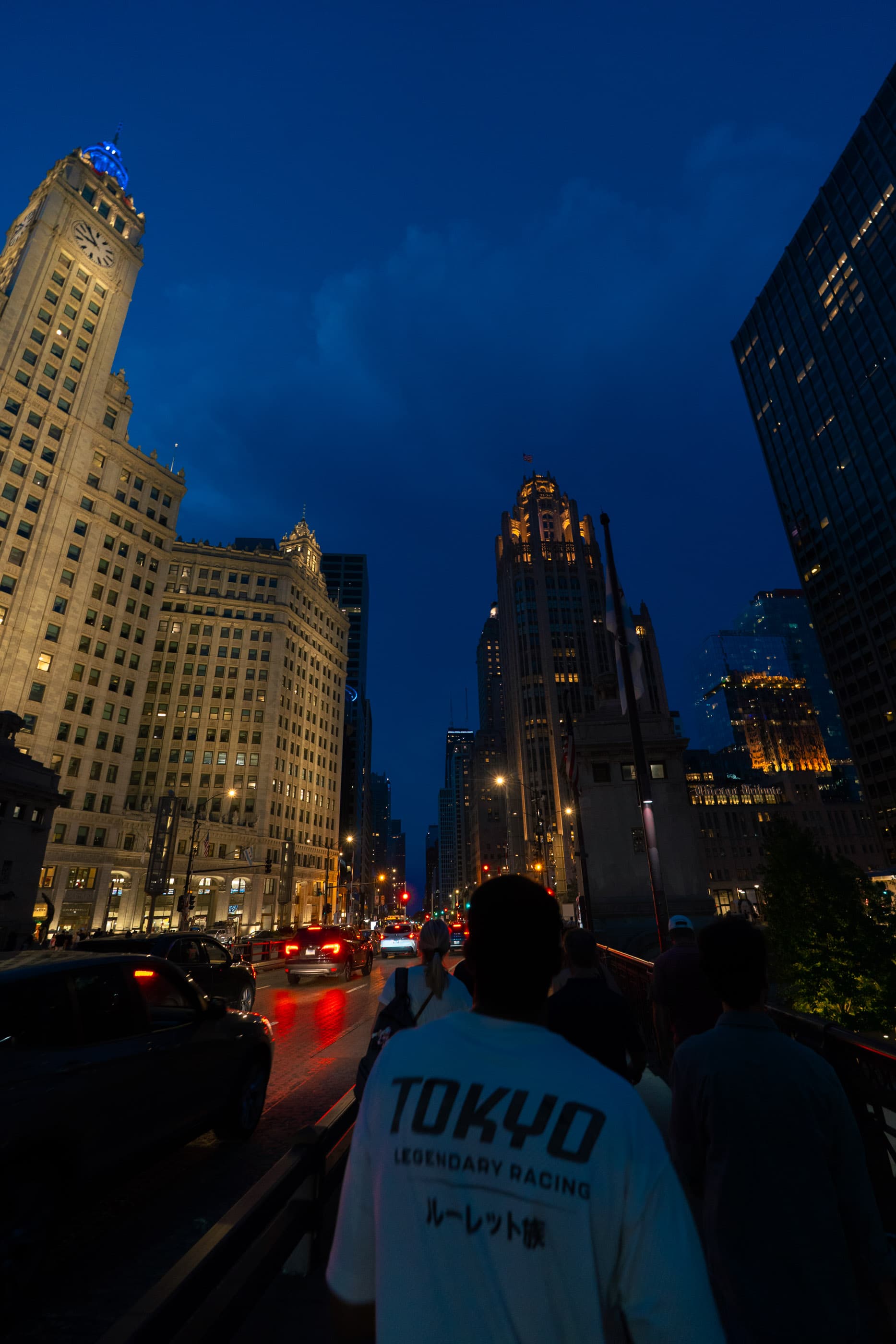 Crowd on a downtown street at blue hour, a man in a Tokyo jacket in the foreground