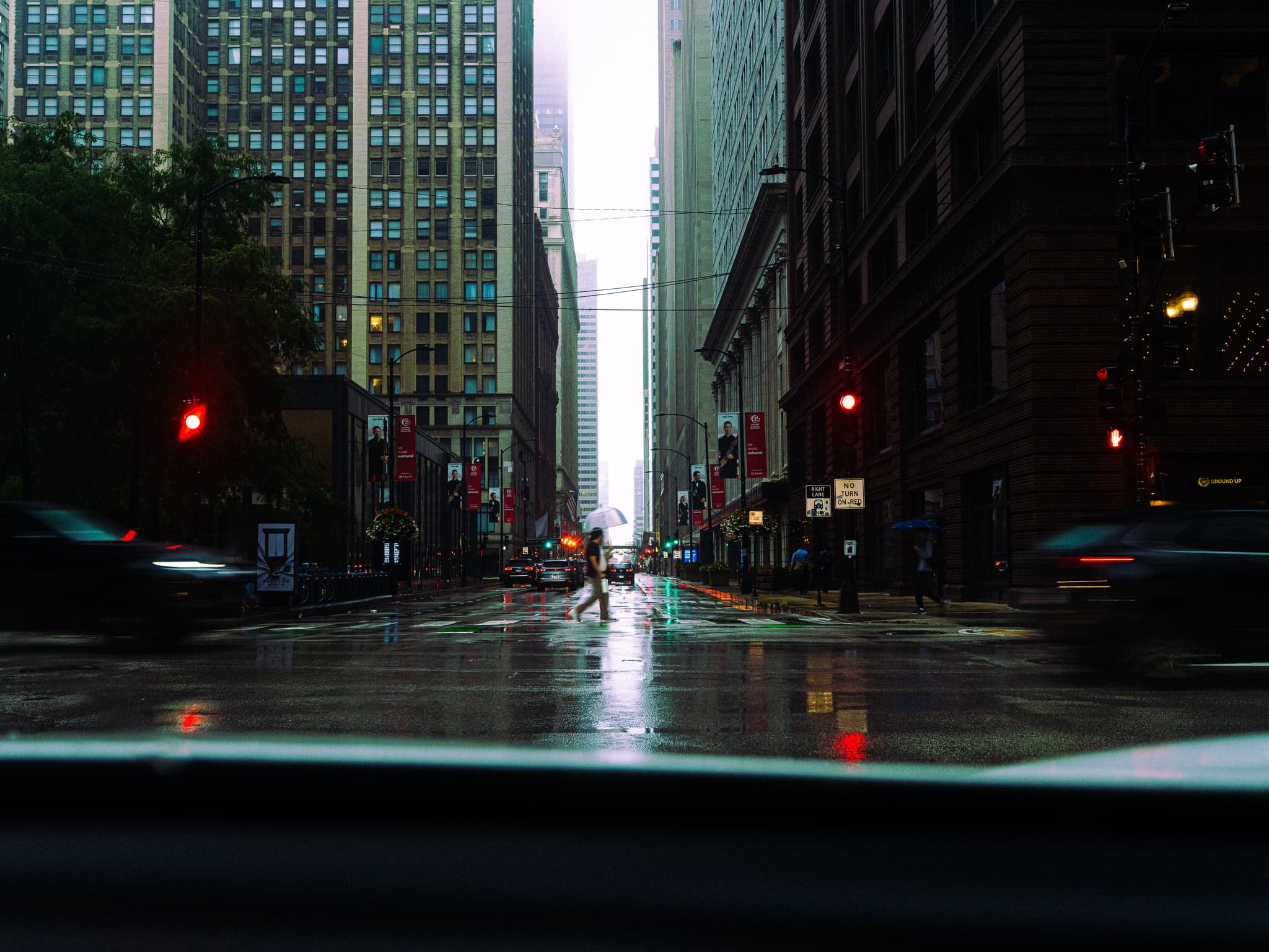 Rain-soaked downtown street at dusk between tall buildings