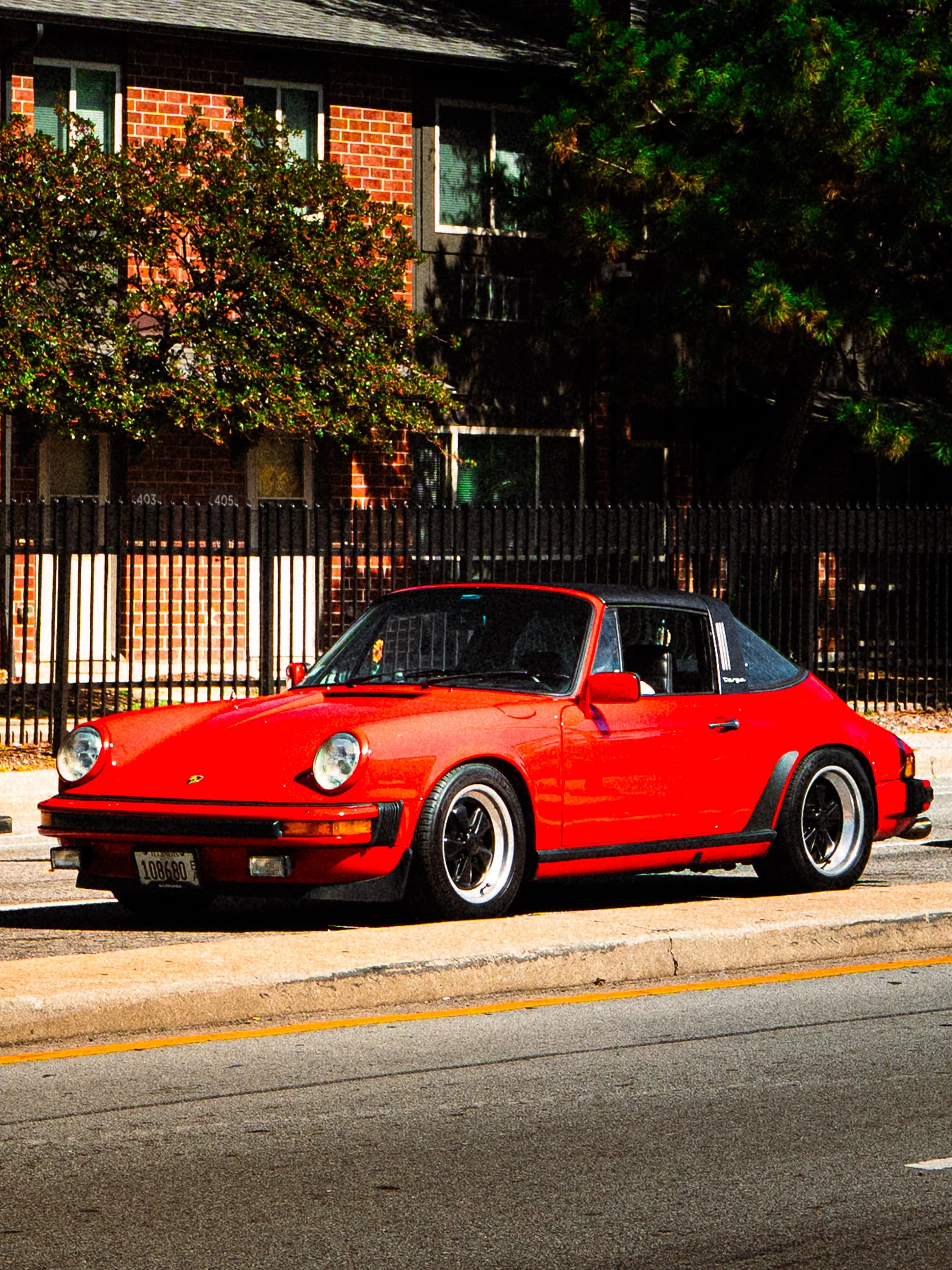 Red vintage sports car parked beside a brick building