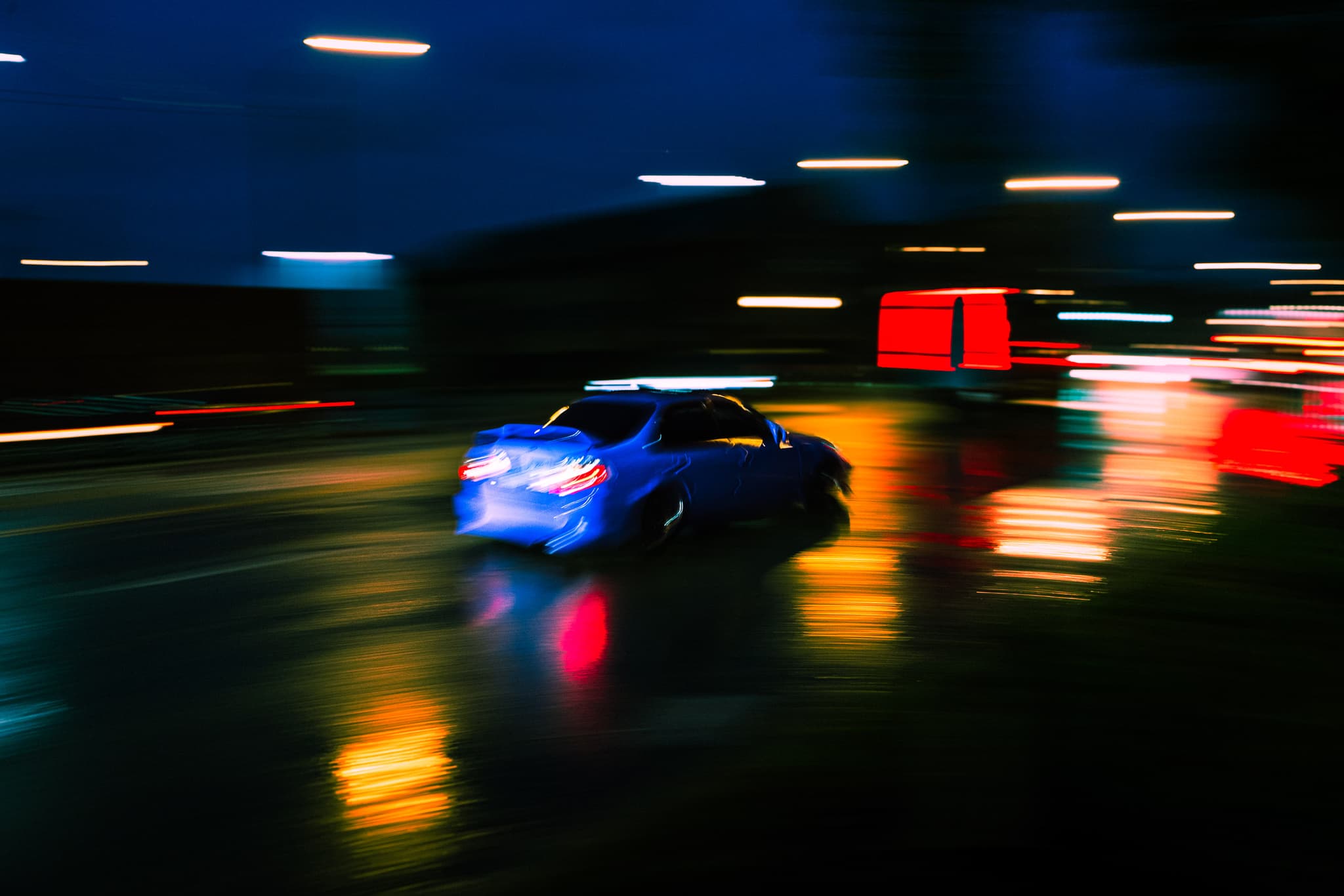 Blue car streaking past city lights at night