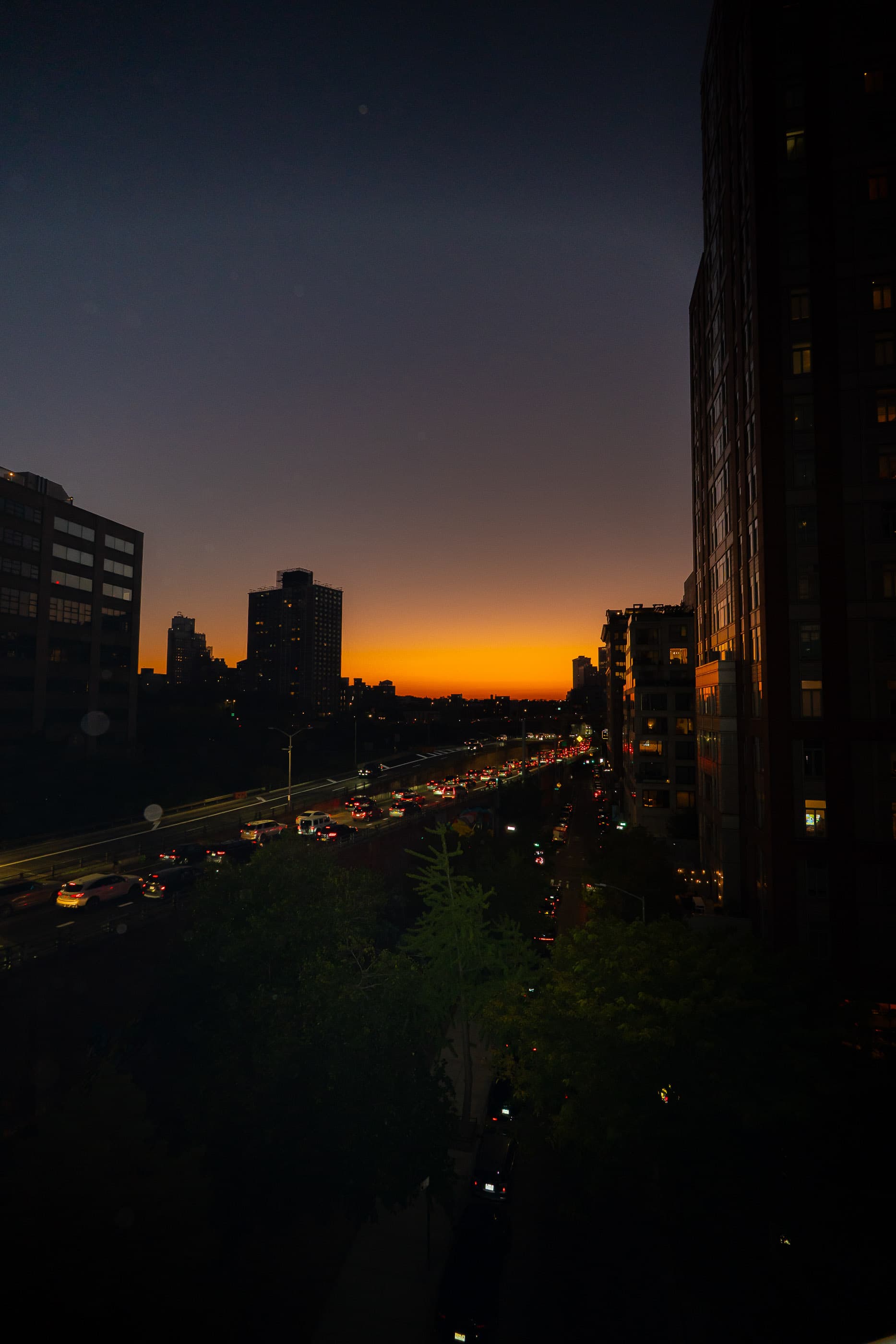 Orange sunset over the city as traffic streams below