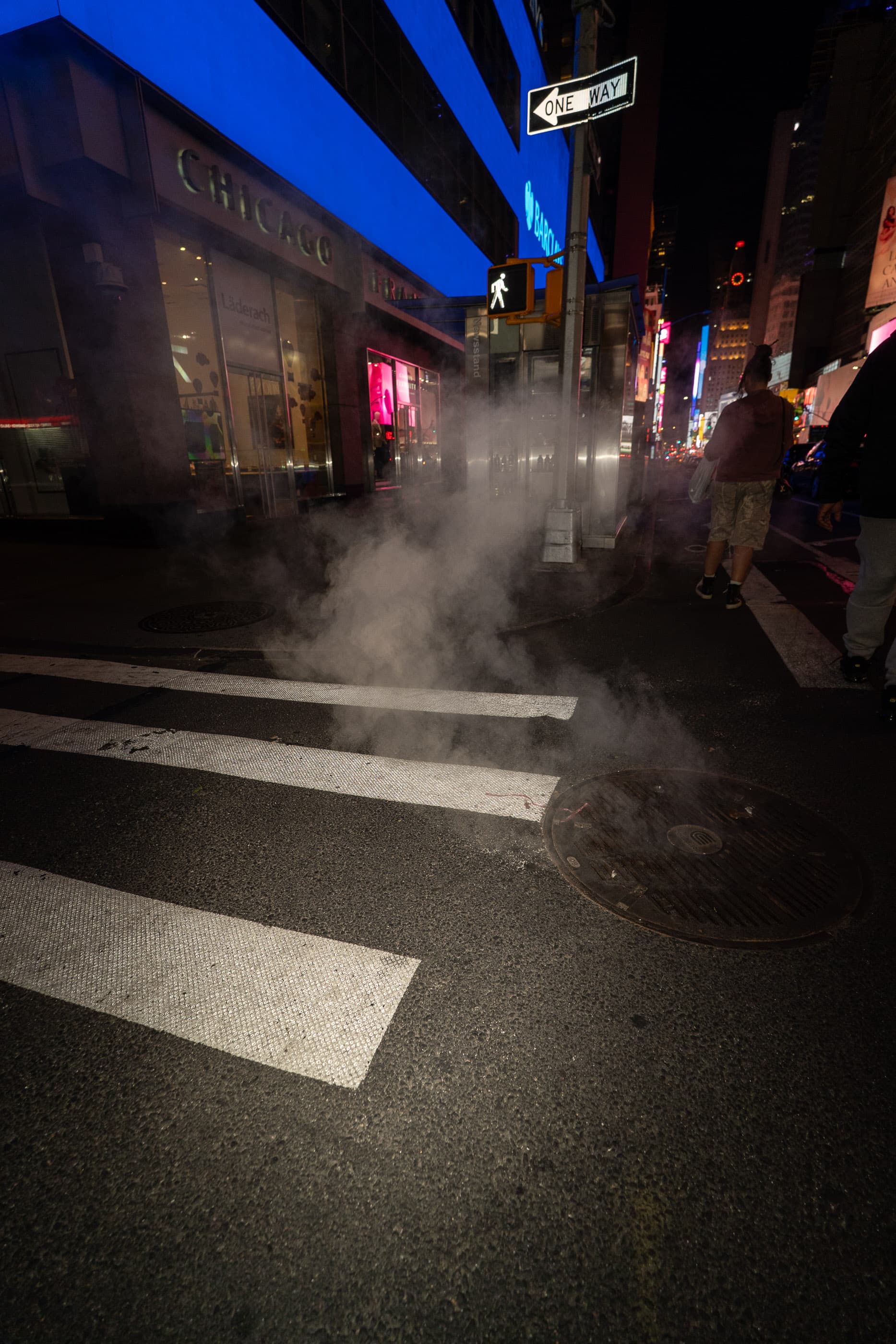 Steam rising from a crosswalk under blue neon at night