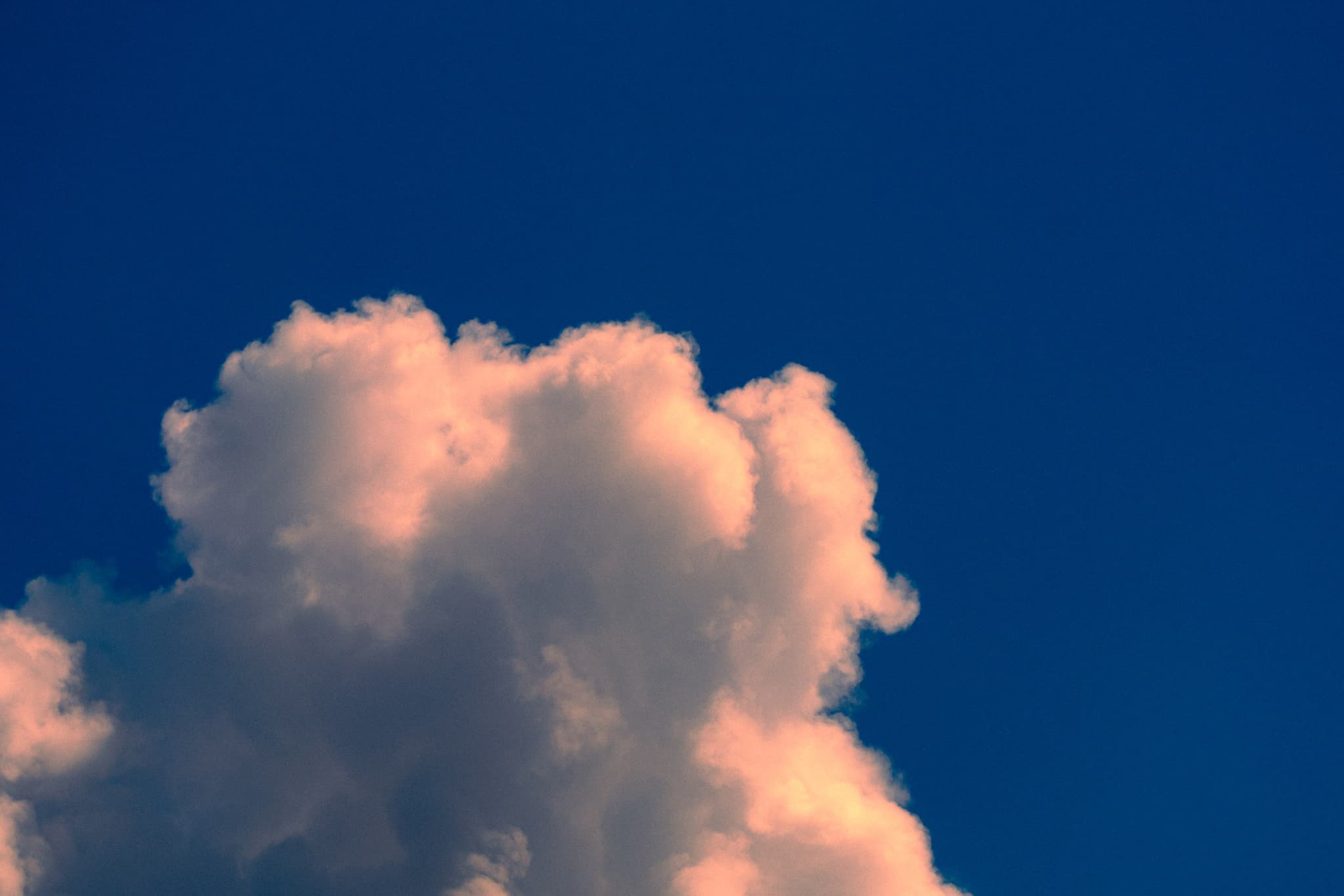 Sunlit cloud against a deep blue sky