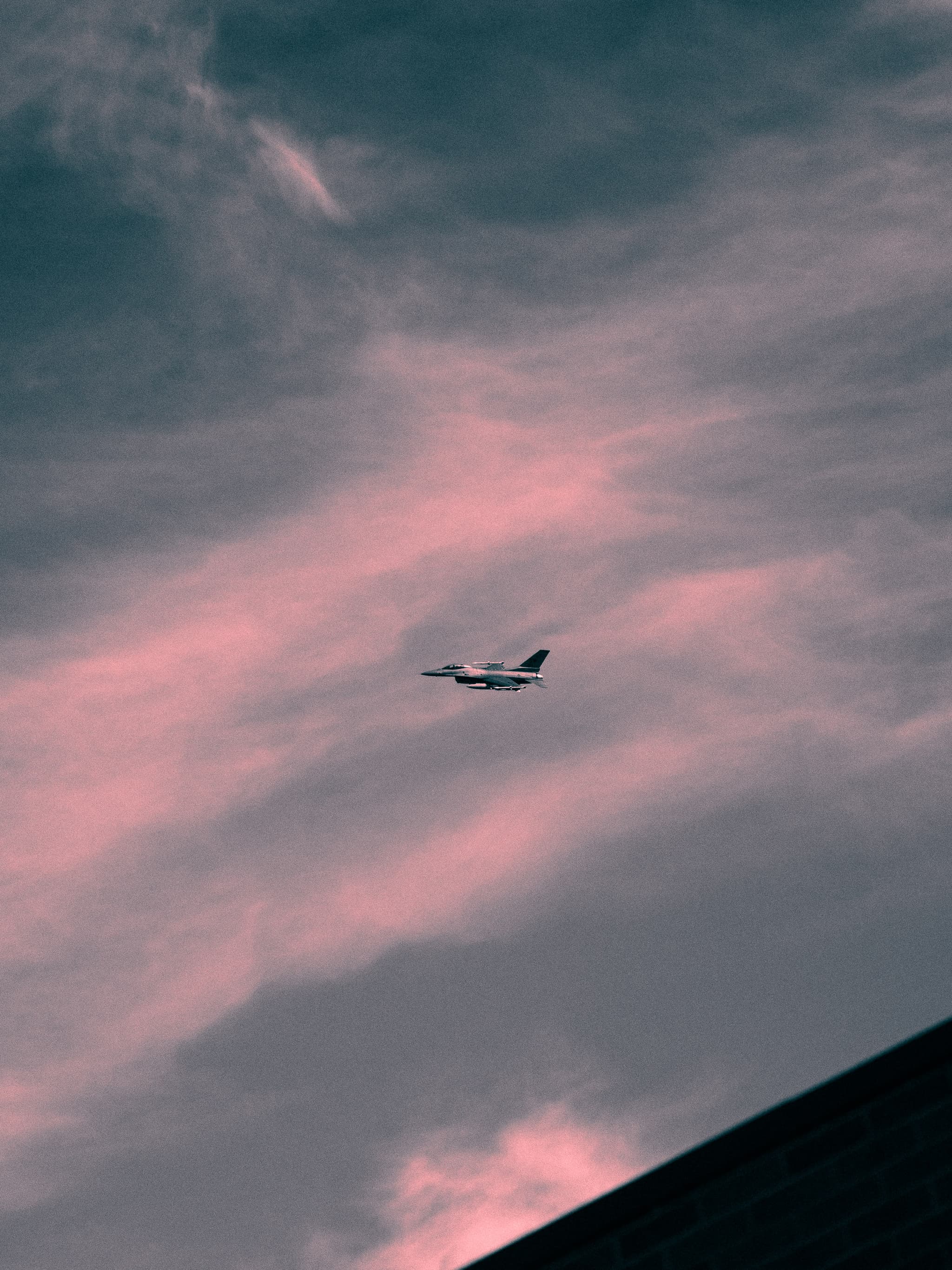 Jet crossing pink clouds at dusk