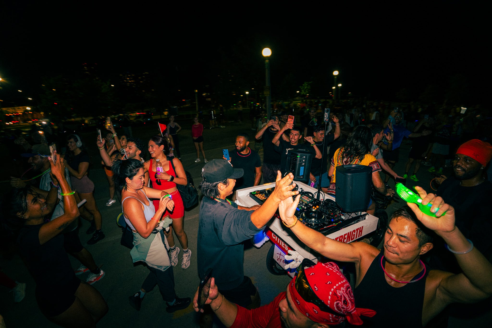 Crowd dancing around a DJ booth at night at the Run The Night 5K
